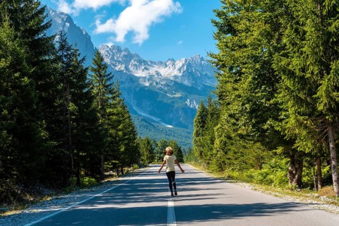 A young tourist woman walking on the road in the Valbona valley, Theth national park, Albanian