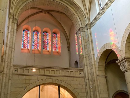 Sun shines through four stained glass windows above main portal of Benedictine Abbey Gerleve casts