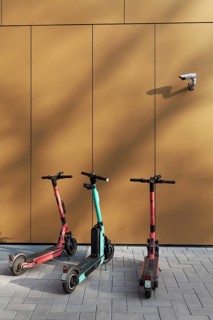 Three e-scooters correctly parked on the pavement, under a surveillance camera, Düsseldorf, North