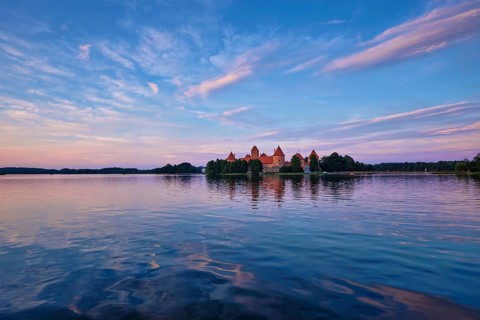 Trakai Island Castle in lake Galve, Lithuania on sunset with dramatic sky reflecting in water.