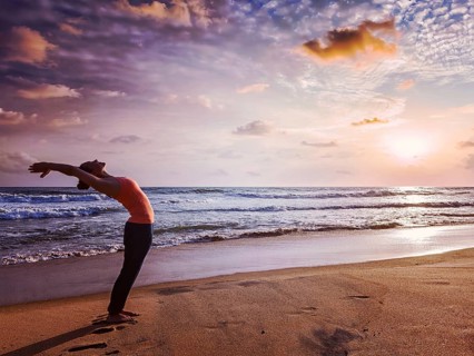 Vintage retro effect hipster style image of young sporty fit woman doing yoga Sun salutation Surya