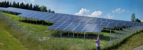 Man photographing a fenced photovoltaic plant, Pfronten, Allgäu, Bavaria, Germany, Europe
