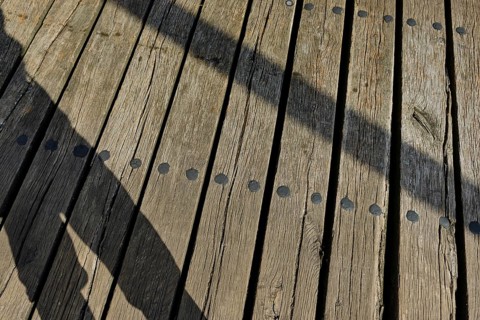 Shadow cast by a person and wooden planks, heritage-protected wooden bascule bridge over the Trebel