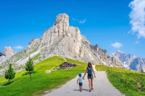 Mother and son walking on a path near the impressive giau pass in the italian dolomites, enjoying