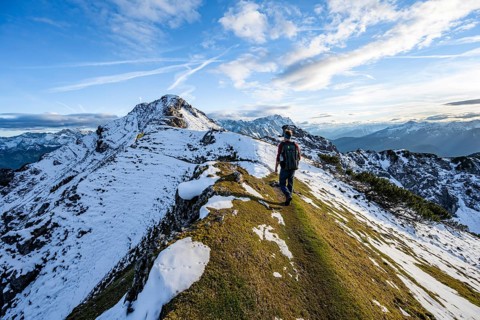 Mountaineer on hiking trail, mountain landscape with snow in autumn, summit and ridge of the