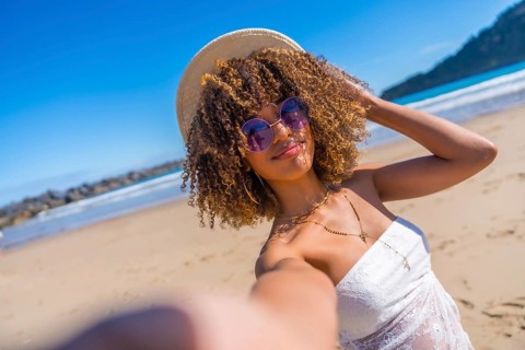 Personal perspective of a cute beauty latin woman in summer clothes, sunglasses and sun hat taking
