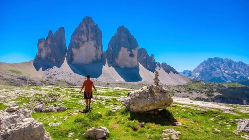 Tourist enjoying the breathtaking view of the tre cime di lavaredo peaks while hiking in the