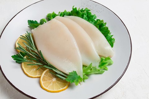 Fresh body, squid, raw, three carcasses, top view, no people, on a plate