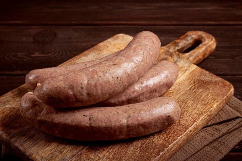 Raw sausages in English with bacon, for grilling, on a cutting board, top view, no people