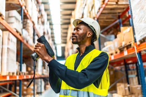 African man using a wireless scan to do inventory in a warehouse