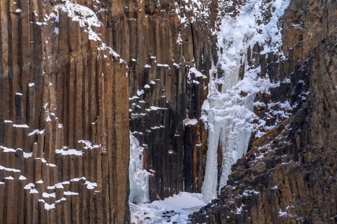 Hengifoss waterfall frozen in the cold winter of Iceland, volcanic cliffs