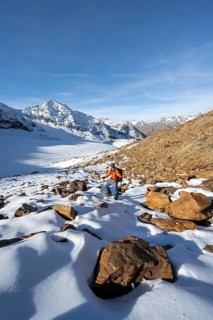 Mountaineer on a hiking trail with snow, descent from Ramoljoch at Spiegelferner, autumnal mountain