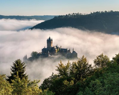 View of the Reichsburg Cochem in autumn, morning mist in the Moselle valley, Cochem,
