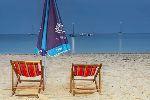Abandoned deckchairs and parasol after sunset at Charlie Beach, Koh Mook Island, Andaman Sea,