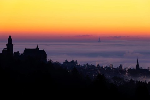 The silhouette of the town of Kronberg im Taunus stands out from the fog and cloud cover that