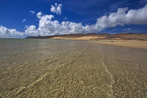 Beach Playa Risco del Paso, Playa de Sotavento with clear water, blue sky and white clouds,