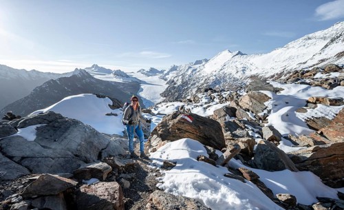 Mountaineer in front of mountain panorama and glacier, mountain hut Ramolhaus in autumn with snow,