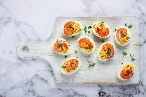 Boiled eggs stuffed with yolk and seasoned with mayonnaise, stuffed eggs with shrimp, on a white