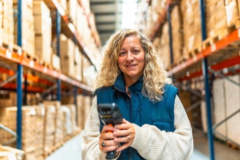 Frontal portrait of a caucasian woman holding a wireless scanner working in a distribution
