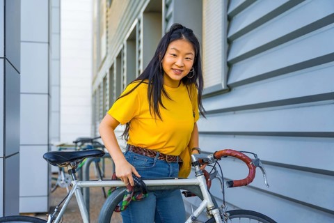 Portrait of a young chinese cute woman parking a bike in the street