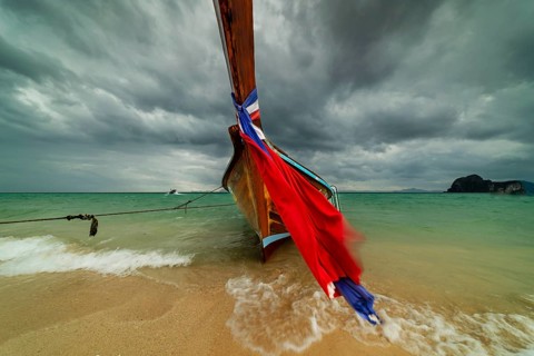 Longtail boat on the beach, dark rain clouds behind, Koh Ngai Island, Andaman Sea, Satun Province,