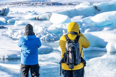 A couple of tourists looking at floating icebergs in Jokulsarlon glacier lagoon in Iceland