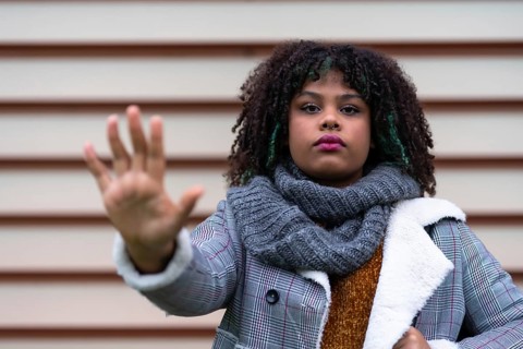 Black ethnic woman making a stop racism gesture on a gray wall
