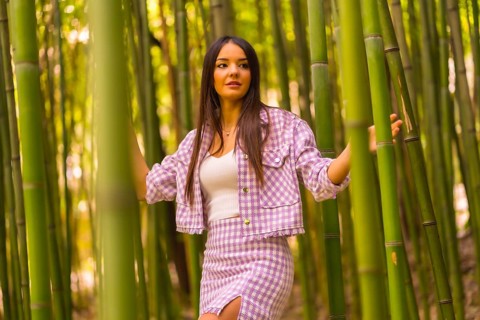 Young caucasian girl with a pink skirt in a bamboo forest. Enjoying the city on summer vacation in