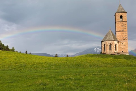 Church St. Kathrein, 39010 Hafling, Italy with a rainbow in the background. The church is from the