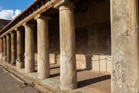 Old large building covered with terracotta clay roof tiles and supported by stone columns at the