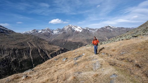 Mountaineers on a hiking trail in Niedertal, snow-covered mountain peaks of the Ötztal Alps with
