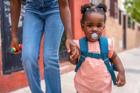 African mother and baby girl walking holding hands in the street