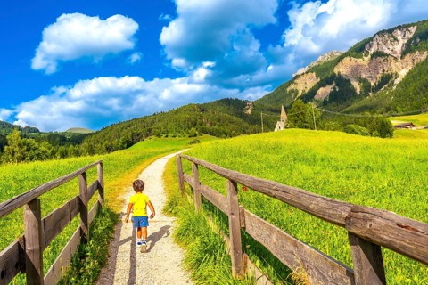Young tourist walking on a path towards the famous st. Magdalena church in val di funes in the