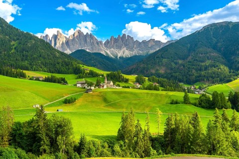 Green meadows blanket the valley in front of santa maddalena village, framed by the stunning odle