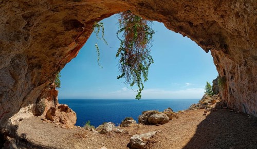 Natural setting of the exit of Limniatis Cave overlooking the sea with rocks and plants, hike from