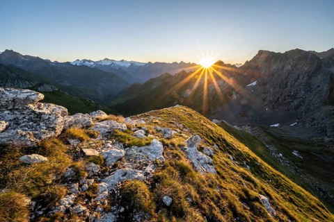 Mountain landscape at sunrise with sun star, view of mountain peaks of the Venediger group and into