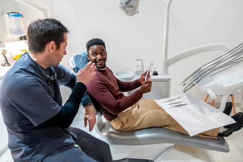 Dentist explaining a dental x ray to a patient sitting in a dental chair, discussing a treatment