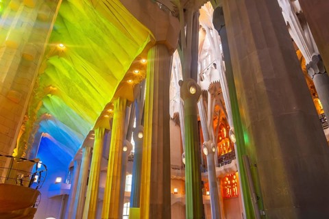 Sunlight illuminates colorful stained glass windows, casting vibrant hues onto architectural