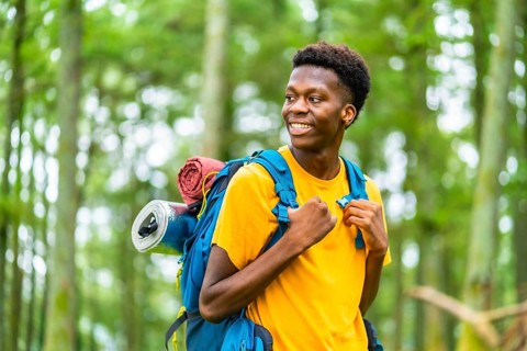 Distracted african young man enjoying nature hiking in the forest