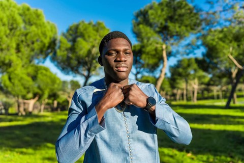 Young african man wearing traditional dashiki attire, adjusting his collar in a serene park setting