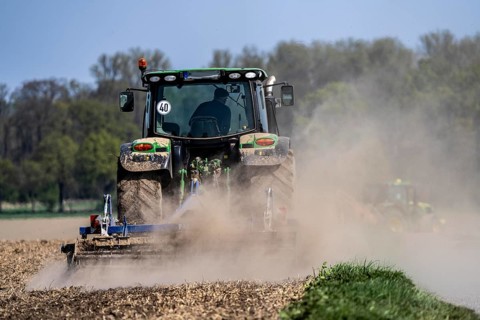 A tractor works a field, due to long dryness in spring, no rain for more than 4 weeks, the fields