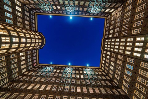 Symmetrical inner courtyard of a Kontorhaus with illuminated rows of windows at night, Hamburg,
