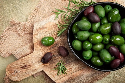 Chalkidiki olives, classic Greek green olives, in a bowl on a cutting board, top view, without