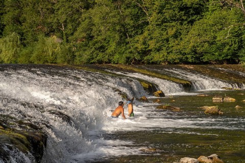 Children bathing at the weir in the Doubs river near Ocourt, Switzerland, Europe
