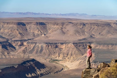 Woman standing on a rock at the edge of the precipice in front of the gorge landscape of the Fish