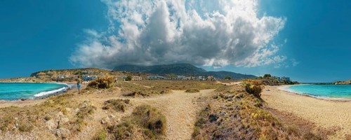 Wide Frangolimiona sandy beach with views of the blue sea, dramatic clouds and a vast coastal
