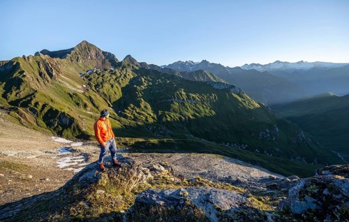 Mountaineer in front of mountain landscape at sunrise, view of mountain peaks of the Venediger
