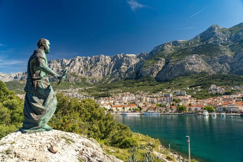 Statue of St Peter in front of the city view of Makarska and the Biokovo Mountains, Croatia, Europe