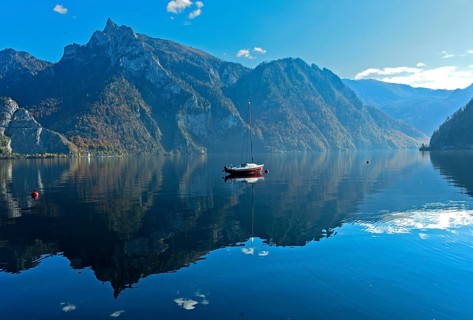 Lonely boat anchored on the mirror-smooth water of Lake Lake Traun, Traunkirchen, Salzkammergut,