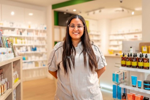 Portrait of a cheerful young female pharmacist with eyeglasses and uniform standing smiling at
